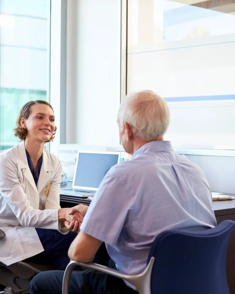 A doctor shaking hands with a patient in the consulting room