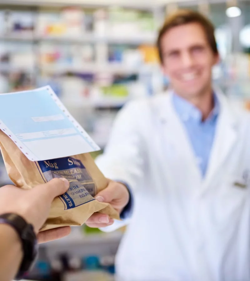 A pharmacist handing over a repeat prescription