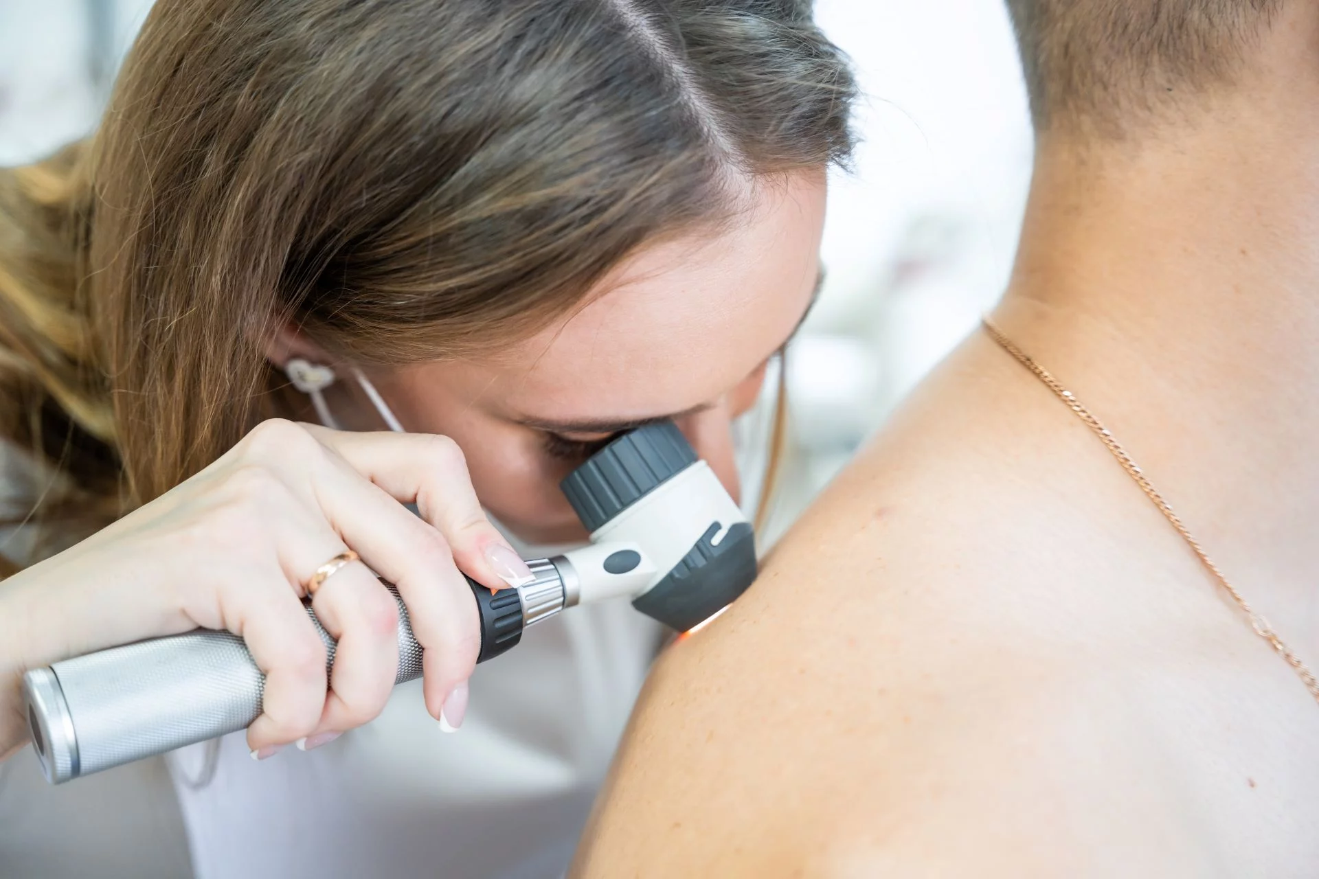 A doctor examining a patient's skin with a dermatoscope