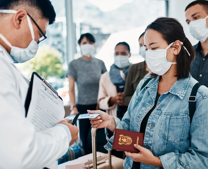 A traveller in a mask handing over a passport